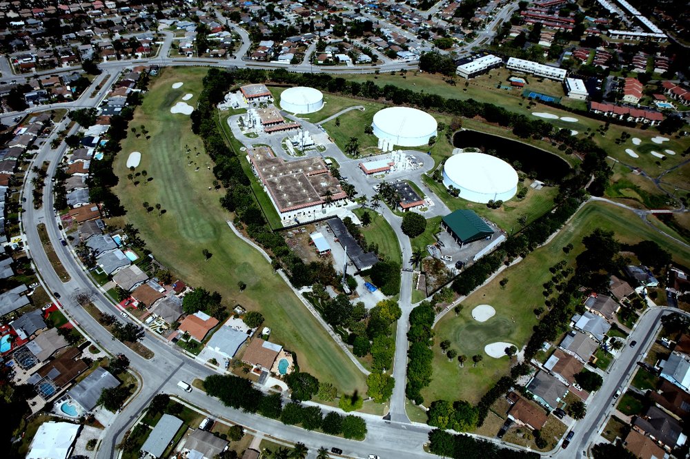 Aerial view of a water treatment facility surrounded by buildings and roads in an urban area.